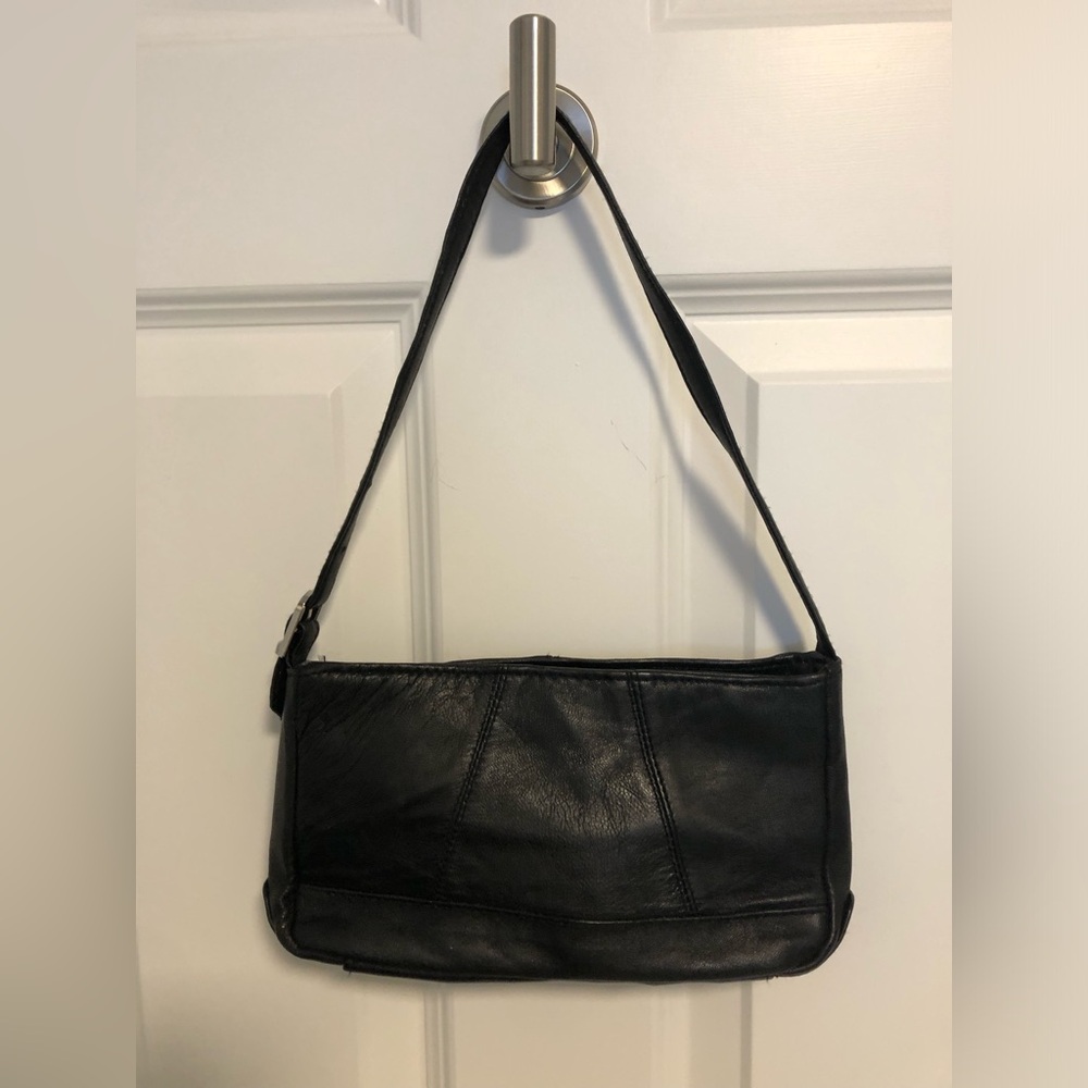 Black leather handbag. Adjustable strap. Zippered top. 5.5H- 9.5 L